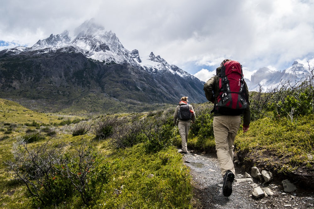 Two hikers walking towards a mountain