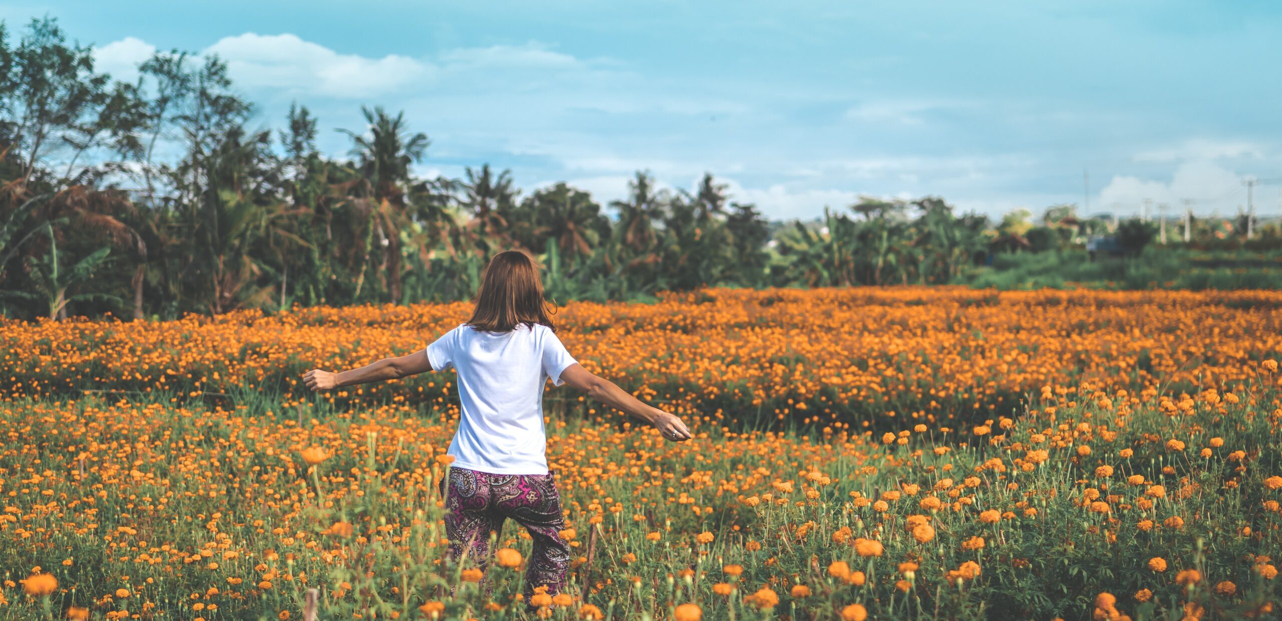 Girl running through field of yellow flowers